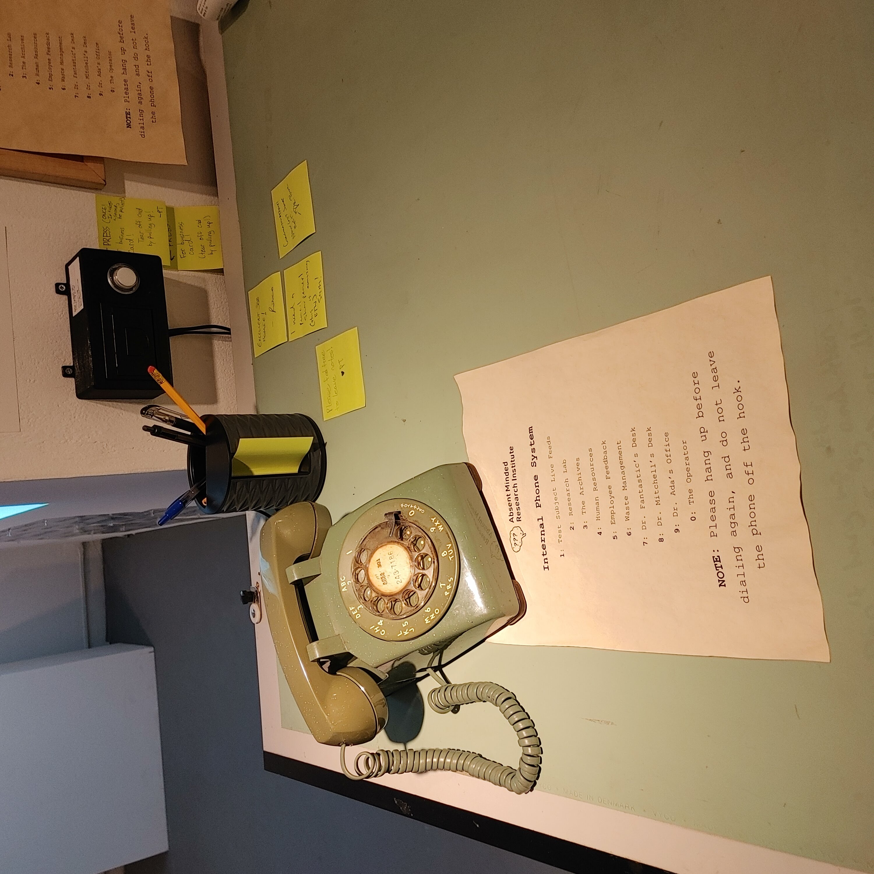 A photo of a green rotary phone on a desk, with a phone menu next to it.